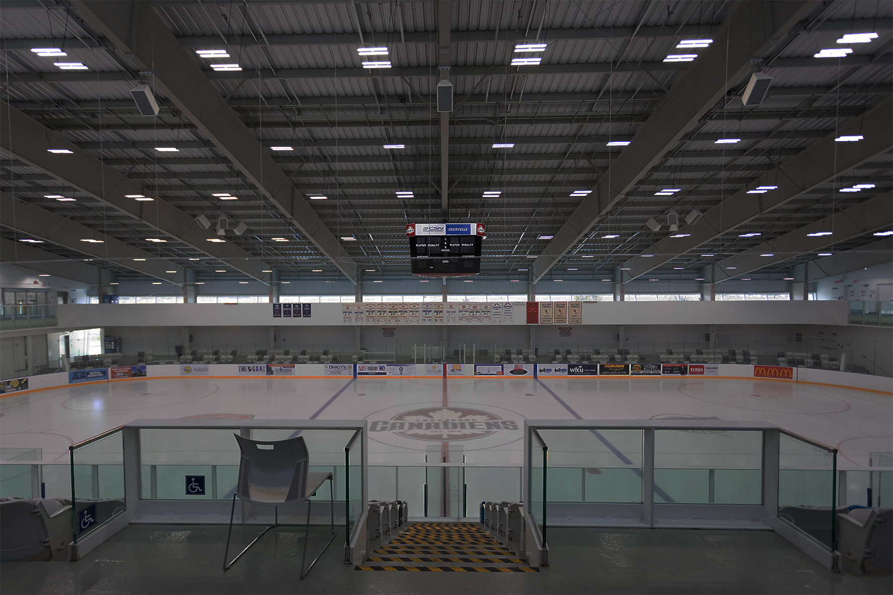 Large ice rink dimly lit surrounded by seating area