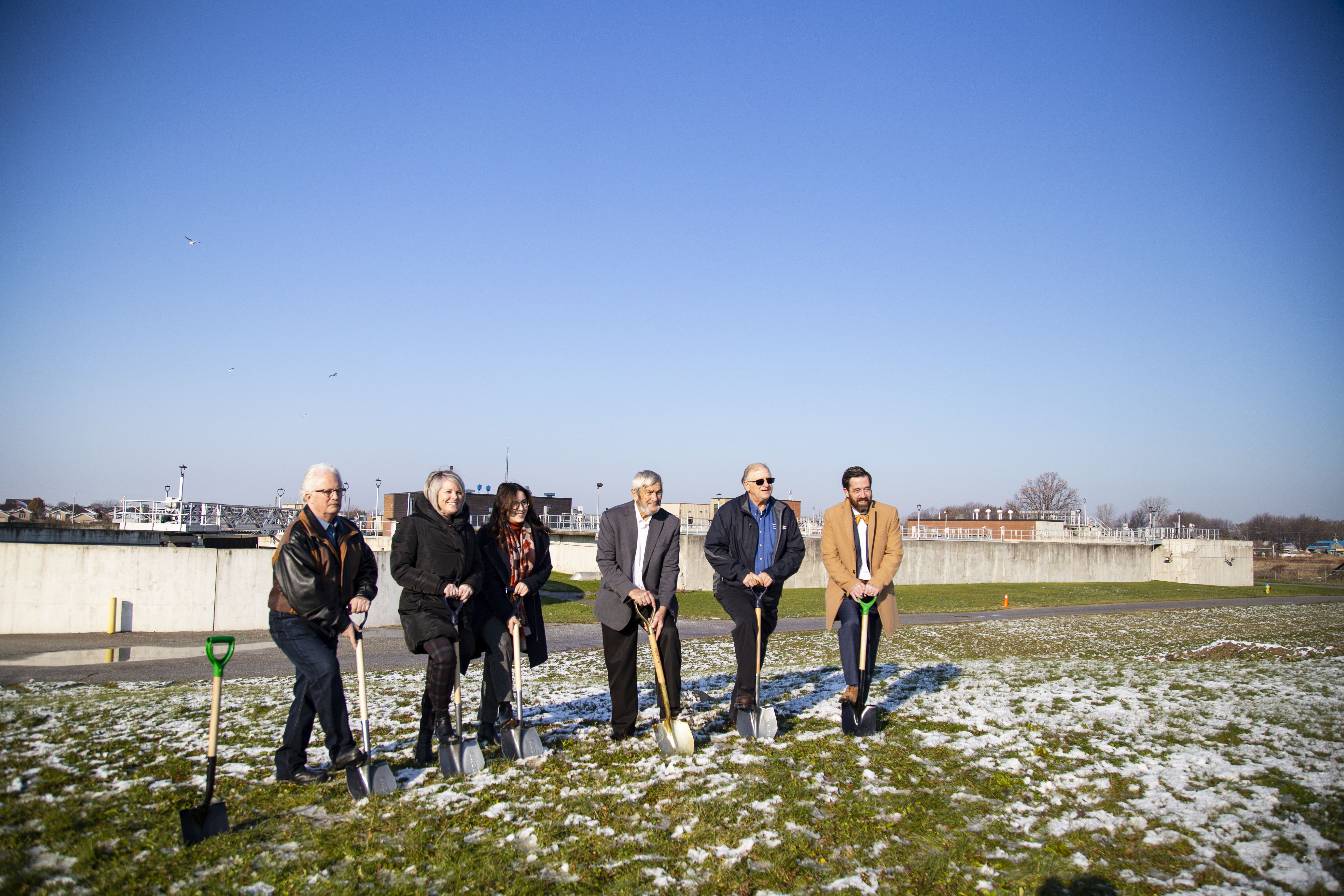 Members of Council in a line preparing for groundbreaking and standing on shovels in front of the current Denis St. Pierre Water Pollution Control Plant.