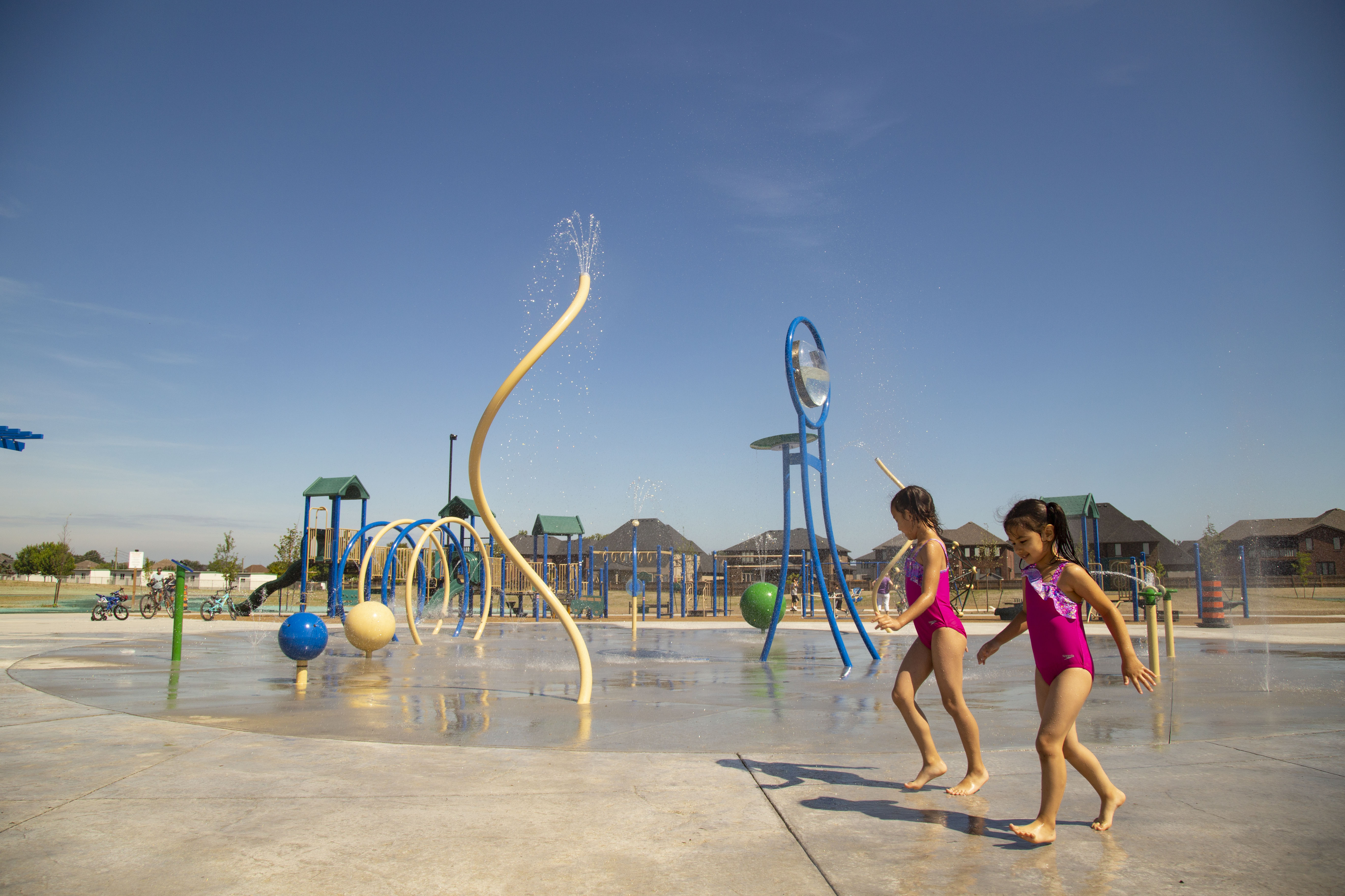 Two kids running in front of the new splash pad at River Ridge Park in Lakeshore.