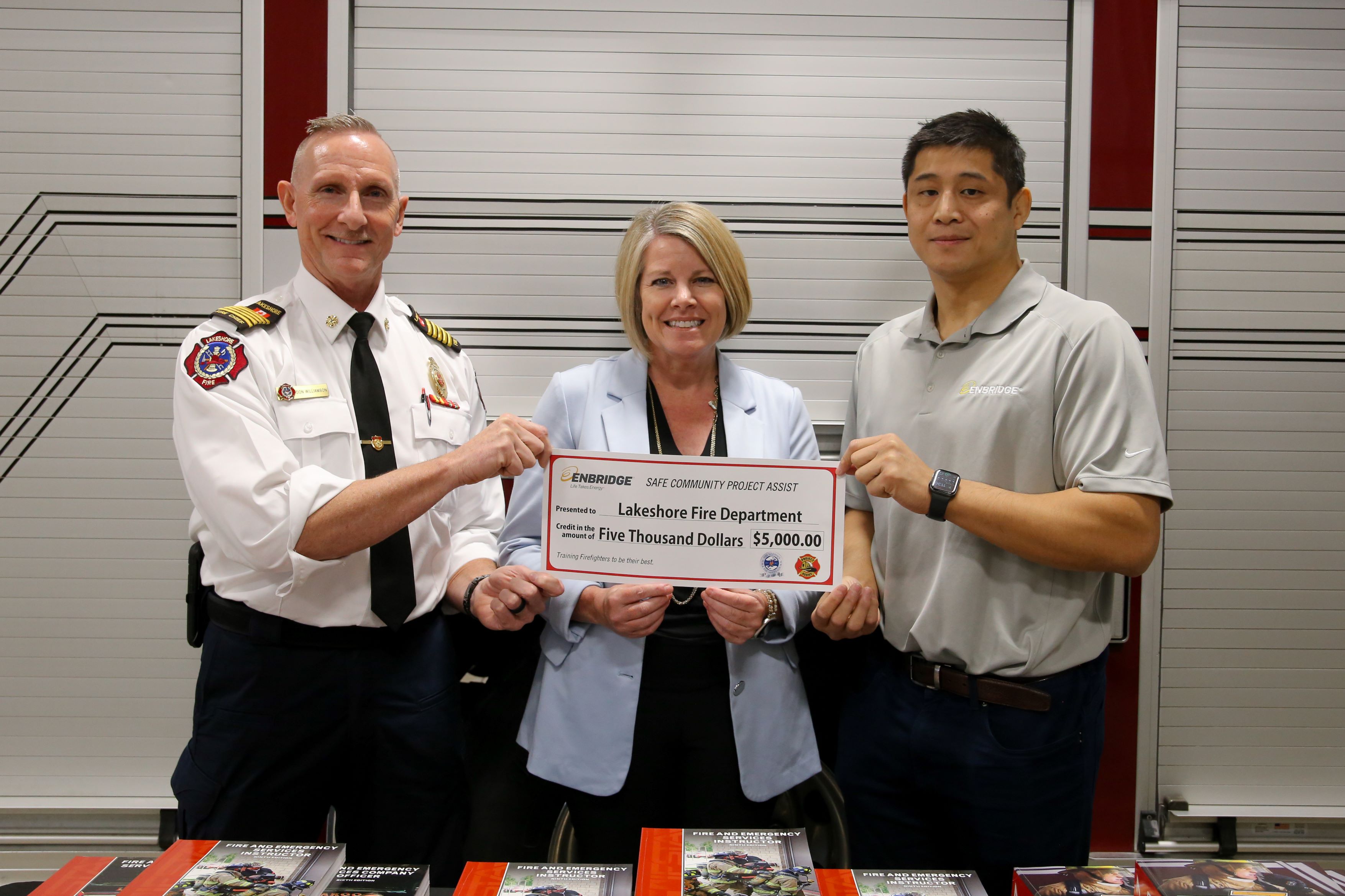Photo of Fire Chief, Mayor, and Enbridge representative holding a $5,000 cheque.