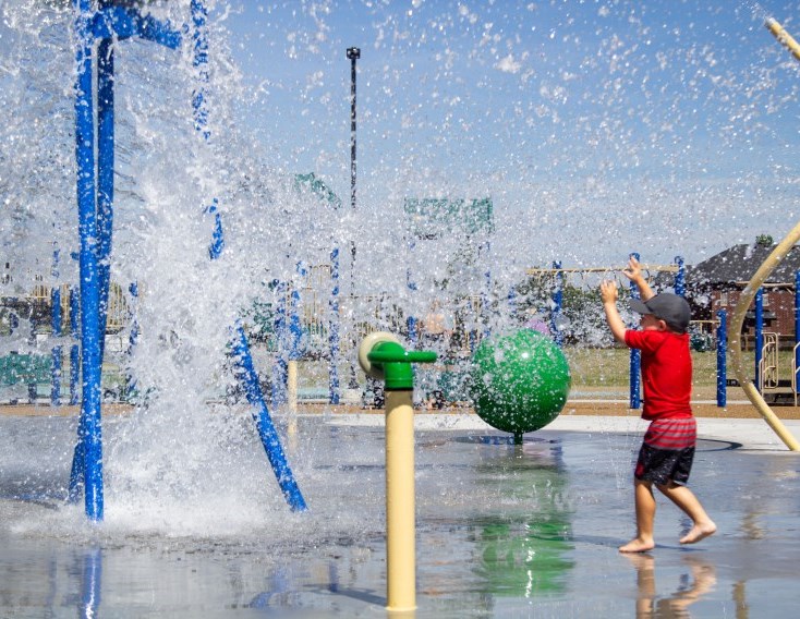Young child splashing at the splash page in River Ridge Park in Lakeshore