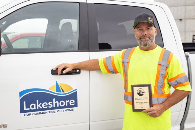 Ron Duquette holding his Truck Roadeo plaque while leaning on a Lakeshore truck.