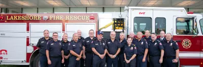 Group of firefighters in front of a firetruck.