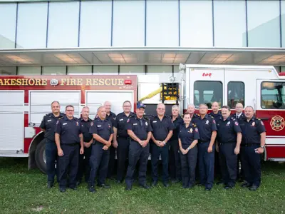 Group of firefighters in front of a firetruck.