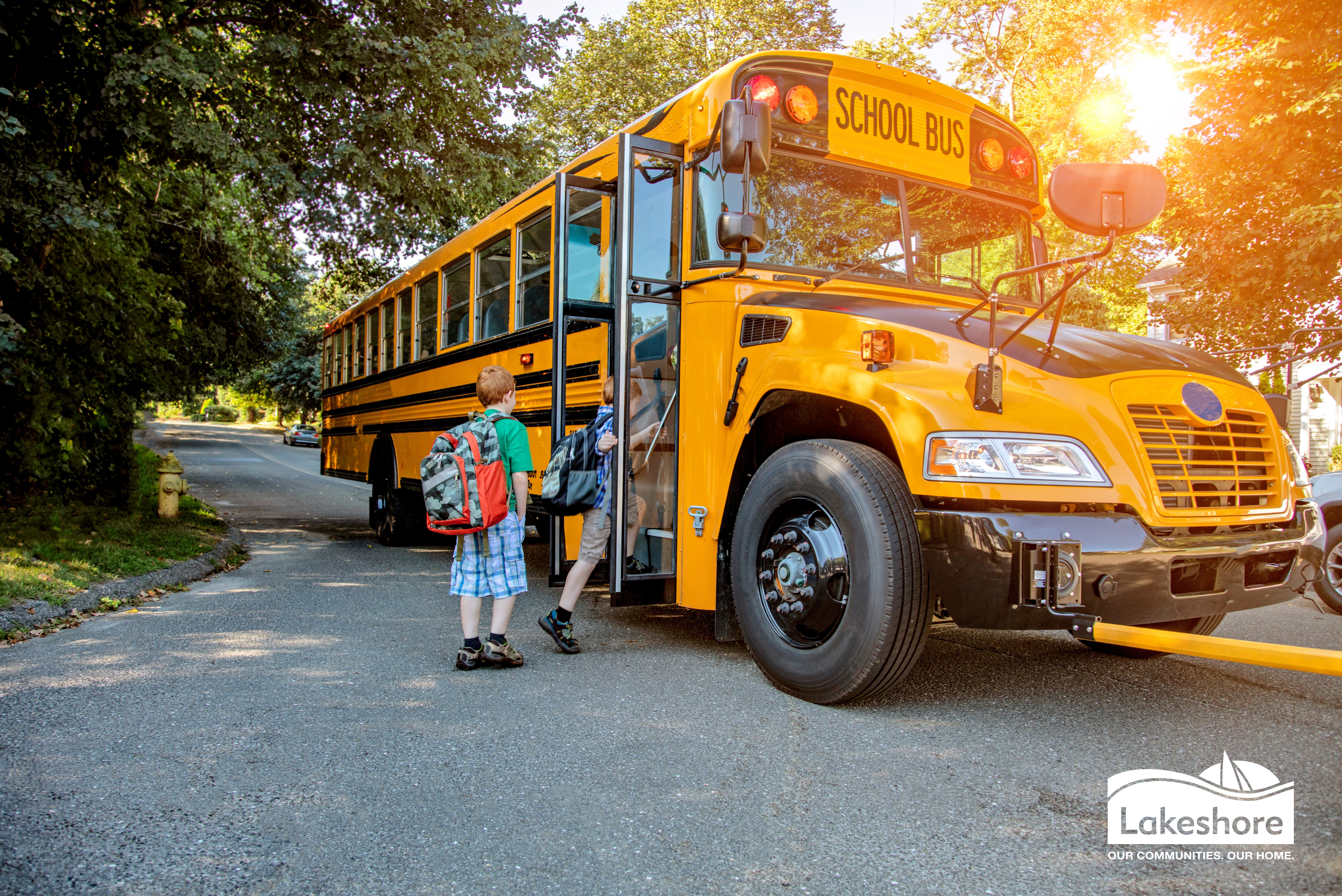 Child getting on a school bus in a residential neighbourhood.