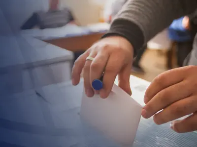 A person dropping their vote into a ballot box.