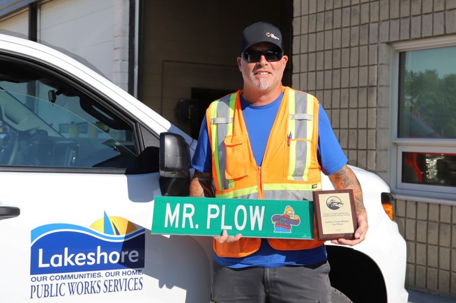 Scott Fick holding his Truck Roadeo plaque in front of a Lakeshore truck.